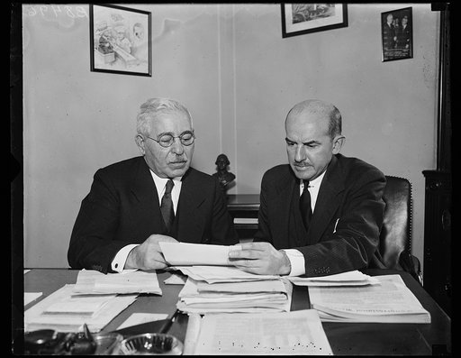 Rep. Adolph J. Sabath, D. of Ill., left, chairman of the Congressional committee investigating real estate and other bond defaults, confers with E.J. Comer, technical advisor to the committee, as Comer prepares to leave for Nashville, Tenn., where he will spend several days looking into the situatio