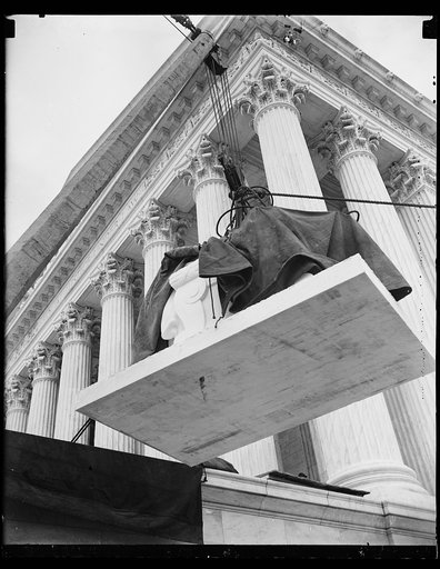 Statue hoisting. This photograph shows the first statue to be placed at the Supreme Court building on its way up. 11/6/35