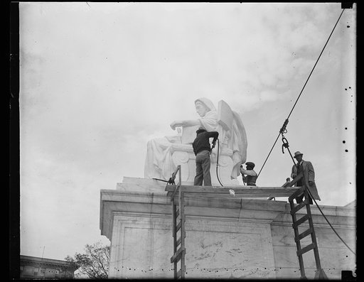 Wash. D.C. Finishing touches. Last minute touches are given the first statue to be placed at the entrance of the new Supreme Court building. (G.A. ? in the overcoat, was the carver for this statue, and James E. Frasier was the sculptor. 11/6/35