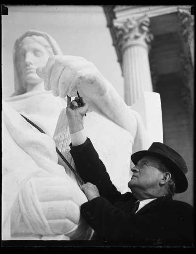 Wash. D.C. Sculptor finishes task., J.E. Frasier, of New York, sculptor, puts the final touches and the official okay on "Contemplation of Justice," one of two statues of his in front of the new U.S. Supreme Court. Working under him as carvers are Gino A. Ratti and E. Jatti, father and son. 11/22/35