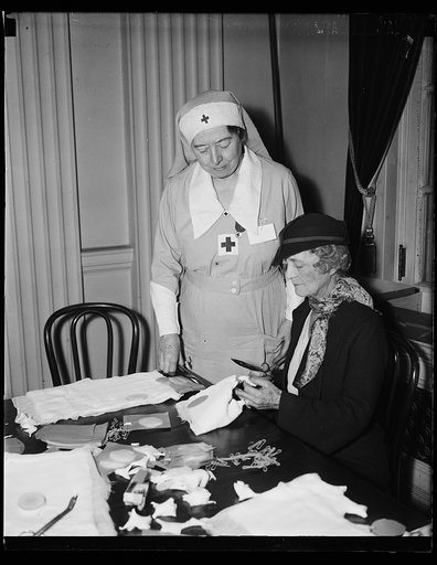 Mrs. Swanson helps Red Cross on bandages. Mrs. Albert T. Niblack, standing, instructs Mrs. Claude Swanson, wife of the Secretary of Navy, in the art of making bandages. Mrs. Niblack is in charge of this work for the American Red Cross in Washington, D.C. The Red Cross has been supplying materials, f