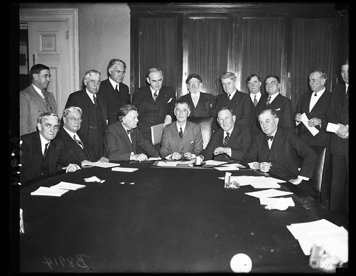 Group at table; includes William Borah, 3rd from right, front row