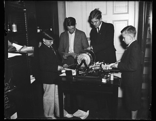 Young men and boys operating copy machine in office
