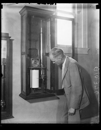 Man with a recording mercurial barograph, an instrument made and perfected by the U.S. Weather Bureau which measures, on a magnified scale, the fluctuations in the pressure of the air