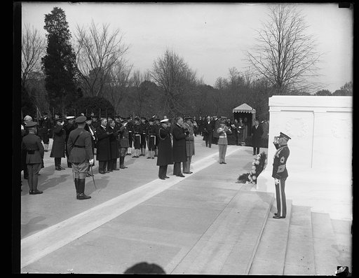 HONORS UNKNOWN DEAD. PRESIDENT ROOSEVELT, IN HIS FIRST ARMISTICE DAY OBSERVANCE IN THE WHITE HOUSE, PLACES A WREATH UPON THE TOMB OF THE UNKNOWN SOLDIER IN ARLINGTON CEMETERY. THE CHIEF EXECUTIVE STANDS BETWEEN TWO WHITE HOUSE AIDES AS TAPS ARE SOUNDED. THE TWO MEN IN CIVILIAN CLOTHES DIRECTLY BEHIN