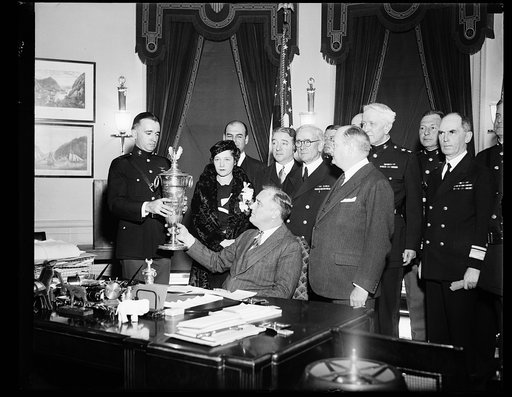 MARINES AVIATION AWARD GIVEN. PRESIDENT ROOSEVELT PRESENTS FIRST LIEUTENANT DAVID LORD, COMMANDING OBSERVATION SQUADRON SEVEN OF THE MARINE CORPS, WITH THE HERBERT SCHIFF TROPHY, GIVEN ANNUALLY TO THE SQUADRON OR UNIT WHICH LOGS THE GREATEST NUMBER OF FLIGHT HOURS WITH THE MINIMUM OF ACCIDENTS. STAN