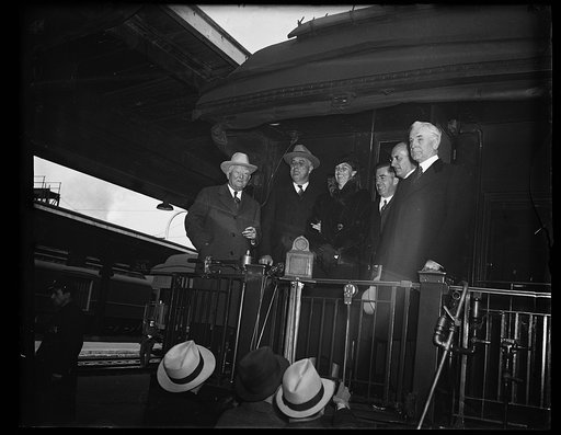 THE CHIEF IS BACK. A LARGE PORTION OF HIS OWN AND OFFICIAL FAMILY GREETED PRESIDENT ROOSEVELT AS HIS TRAIN REACHED UNION STATION TODAY. FROM THE LEFT: VICE PRESIDENT GARNER, PRESIDENT ROOSEVELT, MRS. ROOSEVELT, SECRETARY OF AGRICULTURE WALLACE, ATTORNEY GENERAL CUMMINGS, AND SECRETARY OF STATE HULL