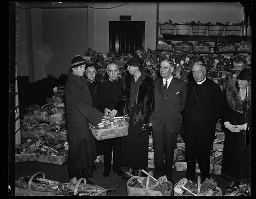 FIRST LADY HELPS SALVATION ARMY DISTRIBUTE BASKETS TO POOR. MRS. FRANKLIN D. ROOSEVELT, IN A DAY OF CHARITABLE ACTIVITIES, JOINED WITH THE SALVATION ARMY IN DISTRIUTING BASKETS OF FOOD TO THE NEEDY. SHE IS SHOWN HERE PRESENTING A BASKET TO MRS. MAY JOHNSON. FROM THE LEFT: MRS. JOHNSON; MRS. JAMES AS