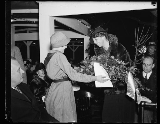 GIRL SCOUTS GIVE FIRST LADY FLOWERS. PAULINE MARTIN, MEMBER OF TROOP NO. 23 OF THE DISTRICT OF COLUMBIA GIRL SCOUTS OF AMERICA, PRESENTS A WREATH OF FLOWERS TO MRS. FRANKLIN D. ROOSEVELT AT THE CHRISTMAS CELEBRATION IN WASHINGTON CHRISTMAS EVE