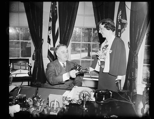 MRS. A.C. CARLSON, NATIONAL PRESIDENT OF THE AMERICAN LEGION AUXILIARY, PRESENTS A VETERAN-MADE POPPY TO PRESIDENT ROOSEVELT. THE ORGANIZATION SELLS POPPIES EACH YEAR TO RAISE MONEY FOR VETERANS SUFFERING FROM WAR INJURIES