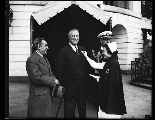 PRESIDENT ROOSEVELT, CENTER, WHO IS PRESIDENT OF THE AMERICAN RED CROSS, IS ENROLLED BY MISS AUGUSTA E. BURTON, NURSE, AS THE FIRST MEMBER IN THE 1935 DRIVE. FROM THE LEFT: ADMIRAL CARY T. GRAYSON, CHAIRMAN OF THE RED CROSS; PRESIDENT ROOSEVELT; CAPT. WILSON BROWN, WHITE HOUSE NAVAL AIDE; AND MISS B