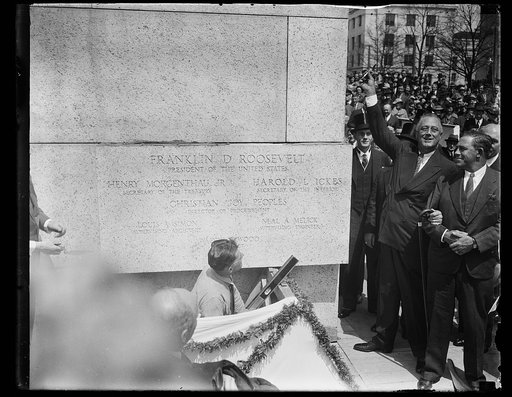 PRESIDENT ROOSEVELT AT CORNERSTONE CEREMONIES. WASHINGTON, D.C. APRIL 16. PRESIDENT ROOSEVELT WAS IN A HAPPY MOOD TODAY AS HE ATTENDED THE LAYING OF THE CORNERSTONE CEREMONIES OF THE NEW $12,000,000 INTERIOR BUILDING. THE PRESIDENT IS HOLDING THE THE TROWEL USED BY GEORGE WASHINGTON WHEN HE LAYED TH