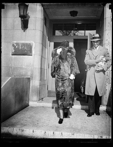 JAMES ROOSEVELT AND MRS. DUPONT AT HOSPITAL. WASHINGTON, D.C. FEBRUARY 22. MRS. EUGENE DUPONT TRYING TO HIDE HER FACE FROM THE PHOTOGRAPHERS AS SHE LEFT THE HOSPITAL WITH JAMES ROOSEVELT AFTER BOTH OF THEM HAD CALLED TO FIND OUT HOW MISS ETHEL DUPONT WAS RECOVERING AFTER HER EMERGENCY OPERATION. ETH