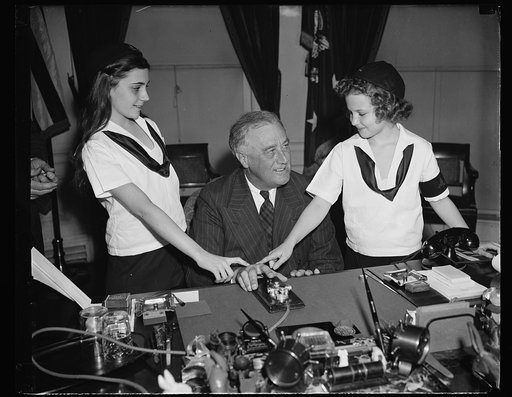 PRESIDENT ASSISTS CAMP FIRE GIRLS IN OPENING NEW NATIONAL HEADQUARTERS IN NEW YORK. WASHINGTON, D.C. MARCH 6. THE MUCH COVETED HONOR OF BEING THE FIRST YOUNGSTER TO PRESS THE HISTORIC GOLD TELEGRAPH KEY USED BY PRESIDENTS WENT TODAY TO CAMP FIRE GIRL JANE BRANDT, RIGHT, AS SHE ASSISTED PRESIDENT ROO