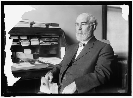 Man, possibly associated with American Peace Society, seated at office desk holding an invitation to attend the annual business meeting of the Chicago Peace Society