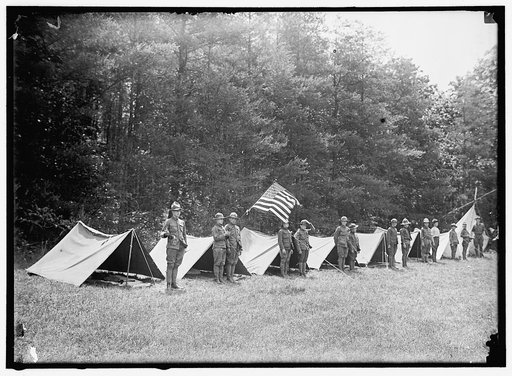 Boy scouts standing in front of tents in encampment