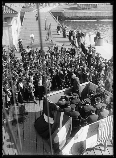 Crowd and photographers assembled at pier; Josephus Daniels? speaking