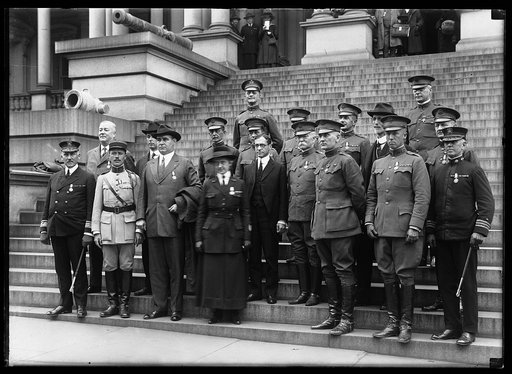 Military group, Newton Baker in dark suit at center; on steps of State, War and Navy Building, Washington, D.C.