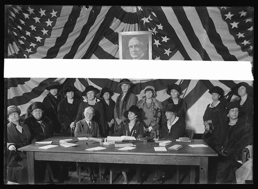 Group seated in front of portrait of Warren Harding; includes Dr. Charles E. Sawyer and Grace Coolidge at table