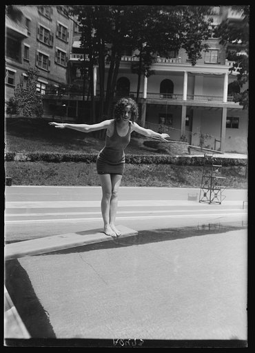 Woman on diving board at swimming pool