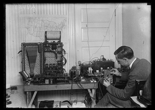 F.W. Dunmore of the radio laboratory of the bureau of standards shown with the radio laboratory in his home. By means of wires extending through his residence he can provide radio entertainment to the bedroom, kitchen, sewing room, sitting room, sleeping porch and basement. He can also make an exten