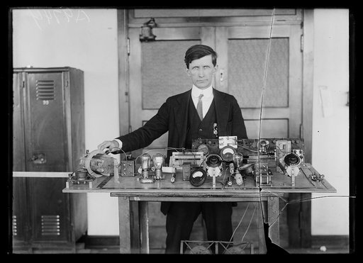 Twelve or thirteen of the naval districts throughout the United States are to be supplied with the short-wave transmitter shown in this photograph. This radio sending equipment, operated between a range of 40 and 80 meters, was designed by A.M. Trogner (shown in the picture) of the naval research la