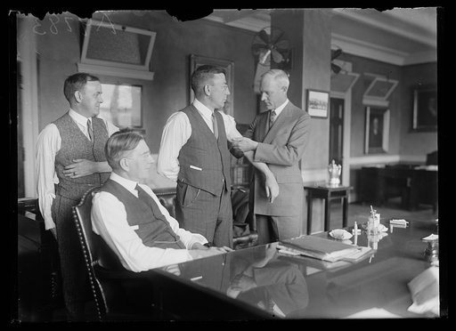 Group receiving shots; Curtis Wilbur seated at desk