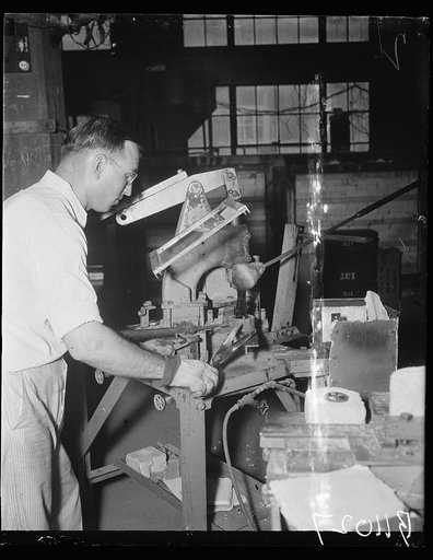 Uncle Sam makes own glass. Washington, D.C. Aug. 24. All optical glass used by the United States Navy is manufactured and finished by the Bureau of Standards in Washington. L. Maxwell, of the Glass Section, Bureau of Standards, is shown cutting molten glass into the mold. He uses ordinary tailor's s