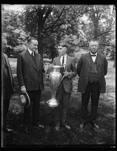 Champion corn grower greeted by president. Young William Pat Boland, 17 years old, of Newberry County, South Carolina, who won a corn growing competition from boys in eight southern states showed his prize cup to President Coolidge at the White House today May, 13th. The cup is worth $2,000