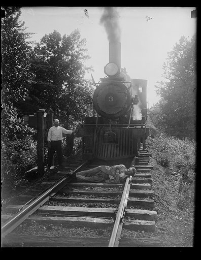 Man lying in front of train on tracks