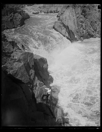 Man climbing rocks near waterfalls, Great Falls?