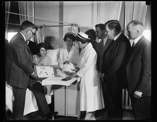 Newborn infant with footprints and group at hospital