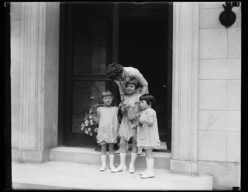 Washington youngsters surprise Mrs. Coolidge with May Day basket of flowers. [...] the First Lady of the land opened the door of [...] morning she found a May Basket of flowers ha[...] nob. The basket, filled with daisies, was pu[...] little Washington children to tell Mrs Coolidge [...] is Child He