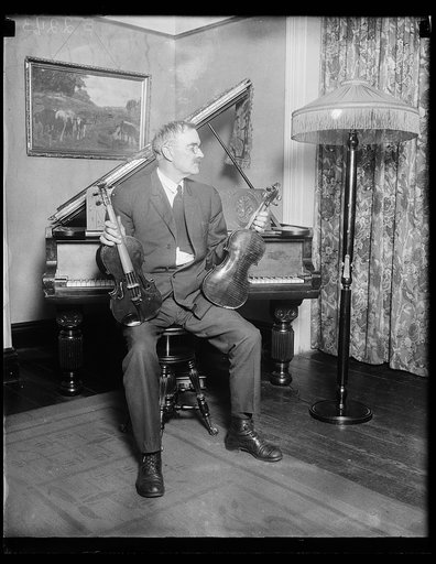 Man at piano holding violins
