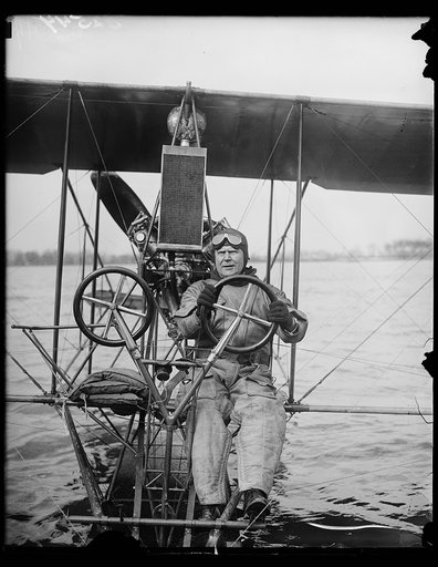 "The good old days of aviation." Commander H.C. Richardson, crack U.S. Navy flyer, at the controls of a 1915 model Curtiss seaplane which he took on its maiden flight today on the Potomac at Washington. The old plane was discovered in storage at the Washington Navy Yard where it has been for over 12