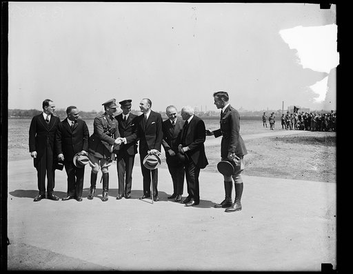 Group at field; Frank Kellogg second from right; U.S. Capitol visible in distance