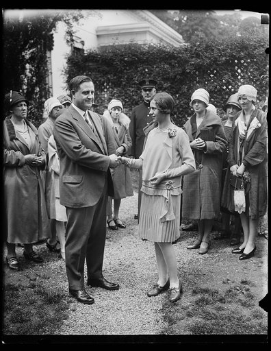 The Secretary to the President, Everett Sanders congratulates Betty Robinson of South Bend, Indiana, on winning the fourth annual National Spelling Bee in Washington. The spelling bee contestants were received by President Coolidge at the White House today