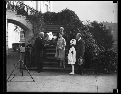 Mrs. Coolidge is presented with original ship model for the 1928 Xmas seals. The original ship model for the 1928 Christmas seals being presented to Mrs. Calvin Coolidge at the White House today by Dr. Kendall Emerson, managinng director of the National Tuberculosis Association. Little Health Crusad
