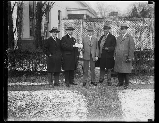 President Coolidge donates to Washington's Community Chest. President Coolidge giving to Robert V. Fleming, Chairman of Washington's Community Chest, a generous donation to the chest. In the photograph, left to right: Elwood Street; Robert Fleming; President Coolidge, Frederick A. Delano; and John P