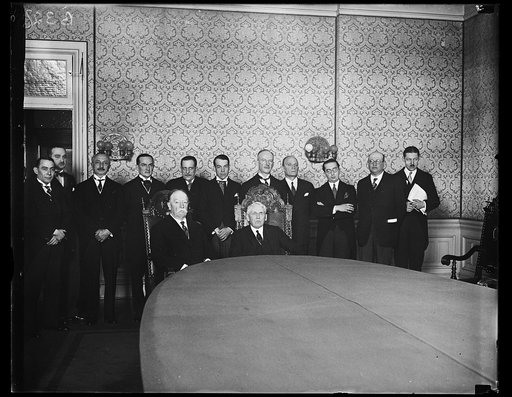 William H. Taft and Frank Kellogg seated at table with group behind