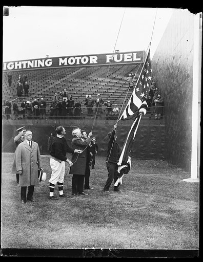 Secretary of War raises flag to pry off baseball lid in Washington. Secretary of War James W. Good with aid of Walter Johnson and Clark Griffith raises the flag in center field shortly before the start of the first game in Washington between the Senators and Athletics