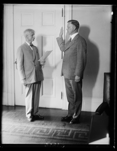 Walter H. Newton, former Representative from Minnesota was sworn in at the White House today as one of the Secretaries to President Hoover N.F. Webster, executive and disbursing clerk of the White House is shown administering the oath of office