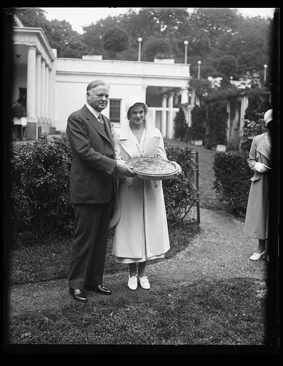 Herbert Hoover and woman with large pie outside White House, Washington, D.C.