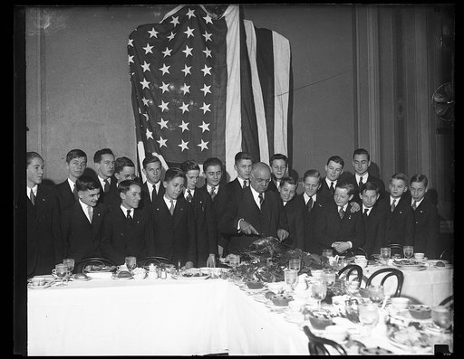 Charles Curtis carving meat at banquet with group of boys