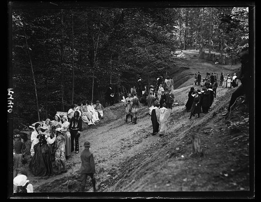 People in costumes in forest and group with motion picture camera