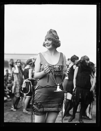 Woman in bathing suit with first prize cup