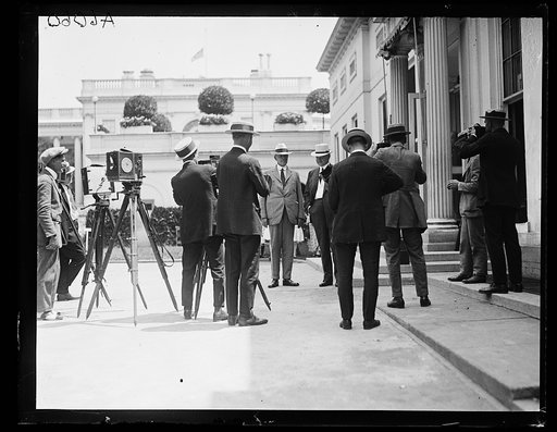 Hubert Work and Herbert Hoover outside White House with group and photographers. Washington, D.C.