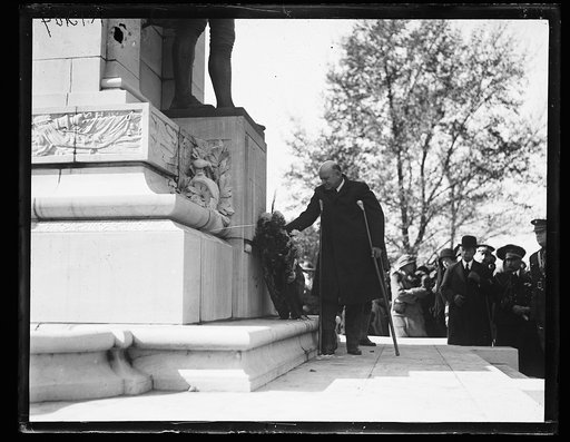 Edwin Denby, on crutches, placing wreath