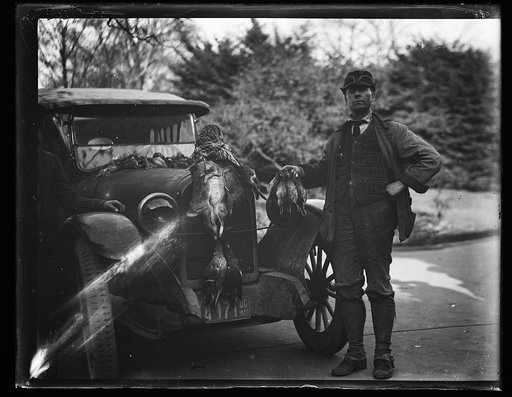Man with automobile and game birds and rabbits