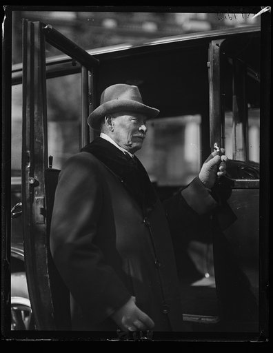 Man at automobile; State, War and Navy Building in background. Washington, D.C.